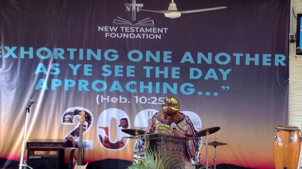 New Testament Foundation minister speaking at the church gathering beneath a backdrop quoting Hebrews 10:25.